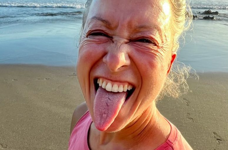 Woman on a beach playfully sticking out her tongue.