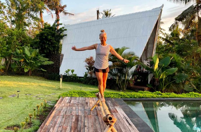 Balancing on a piece of bamboo: A skilled woman maintaining her equilibrium on a narrow bamboo plank.