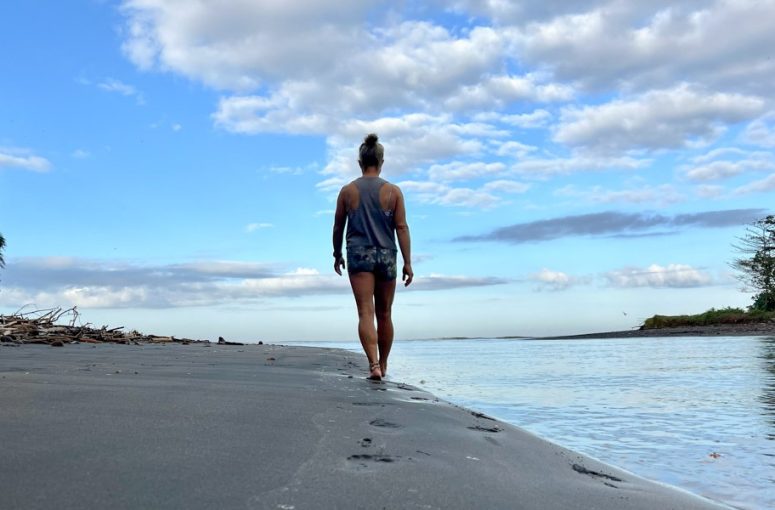 A woman enjoying a peaceful barefoot walk along the sandy beach.